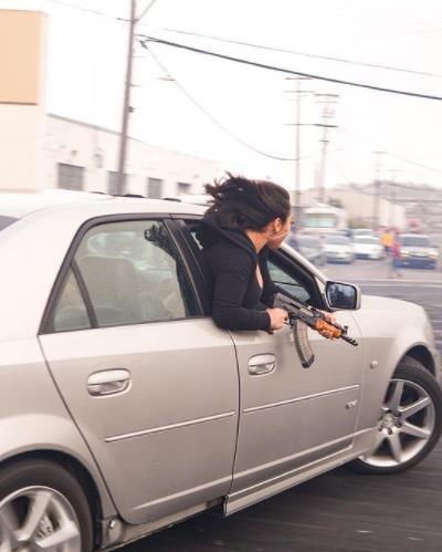 passenger leaning out of a Cadillac holding
                        an AK47